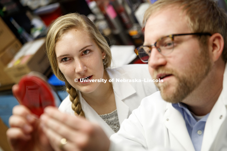 Professor Dustin Loy discuses a sample with Kara Robbins. Robbins is validating Moraxella bacteria as part of her undergrad research project. She is using a new device called a MALDI-TOF. It uses a laser to vaporize pathogens into ions that can be