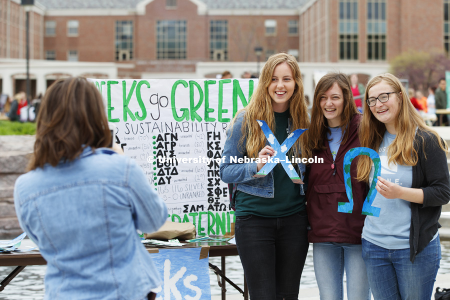 Three ladies pose for a picture in front of the Greeks go Green poster for the Earth Day celebration on city campus. April 21, 2017. Photo by Craig Chandler / University Communication.