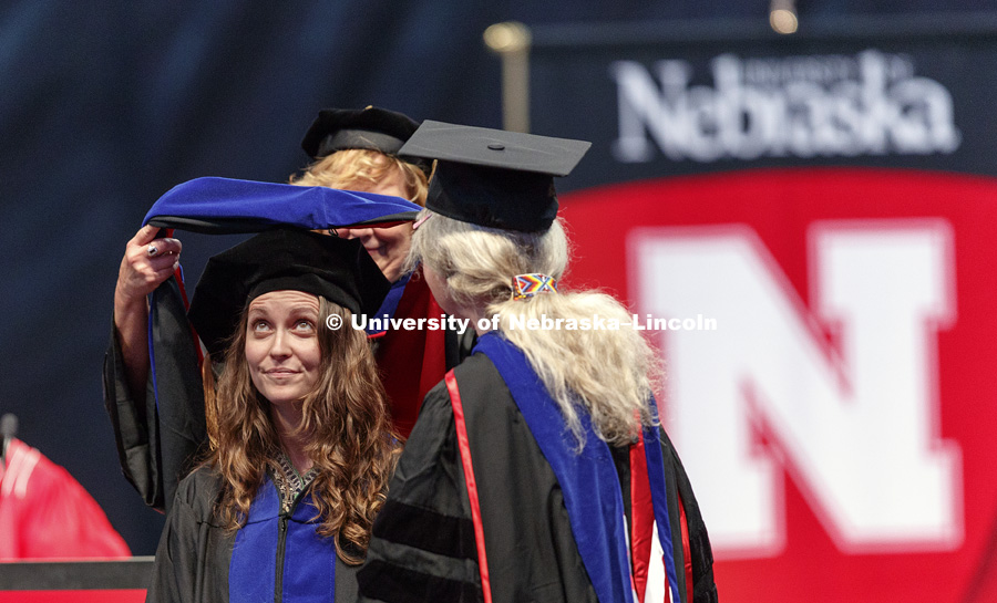 Aubrey Rose Streit Krug watches as her doctoral hood is placed over her head. Students earning graduate and professional degrees received their diplomas Friday afternoon in Lincoln's Pinnacle Bank Arena. Undergraduate commencement is Saturday morning in
