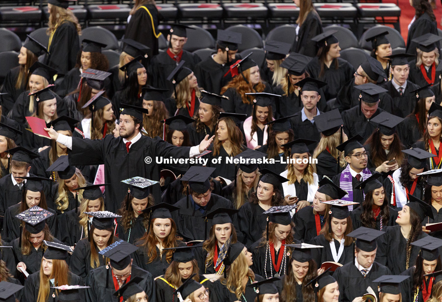 A graduate tries to make it easier for his family and friends to see where he is sitting as the graduates file into the arena. Students received their undergraduate diplomas Saturday morning in Lincoln's Pinnacle Bank Arena. 2452 degrees were awarded