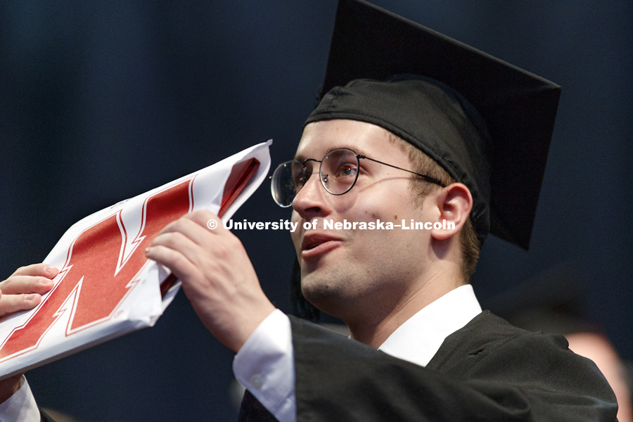 Ryan Rothman shows off his College of Journalism and Mass Communication diploma to his family and friends in the arena. Students received their undergraduate diplomas Saturday morning in Lincoln's Pinnacle Bank Arena. 2452 degrees were awarded Saturday