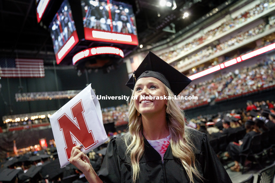 Casey Seberger shows off her College of Journalism and Mass Communication diploma to family and friends in the arena. Students received their undergraduate diplomas Saturday morning in Lincoln's Pinnacle Bank Arena. 2452 degrees were awarded Saturday