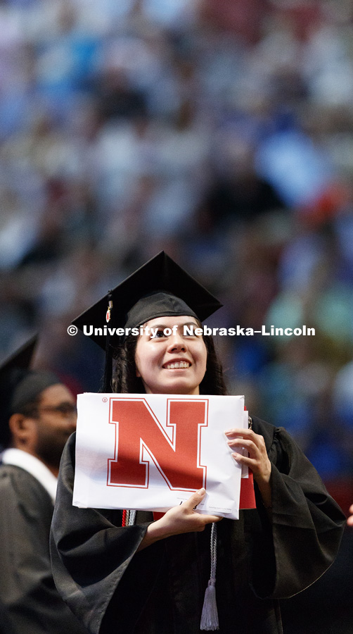 Zully Alejandra Perez Sierra shows off her College of Engineering diploma to family and friends in the arena. Students received their undergraduate diplomas Saturday morning in Lincoln's Pinnacle Bank Arena. 2452 degrees were awarded Saturday morning. May