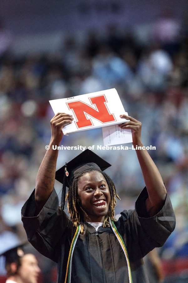 Jonathan Williams holds up his diploma for family and friends after receiving his engineering degree Saturday morning. Students received their undergraduate diplomas Saturday morning in Lincoln's Pinnacle Bank Arena. 2452 degrees were awarded Saturday