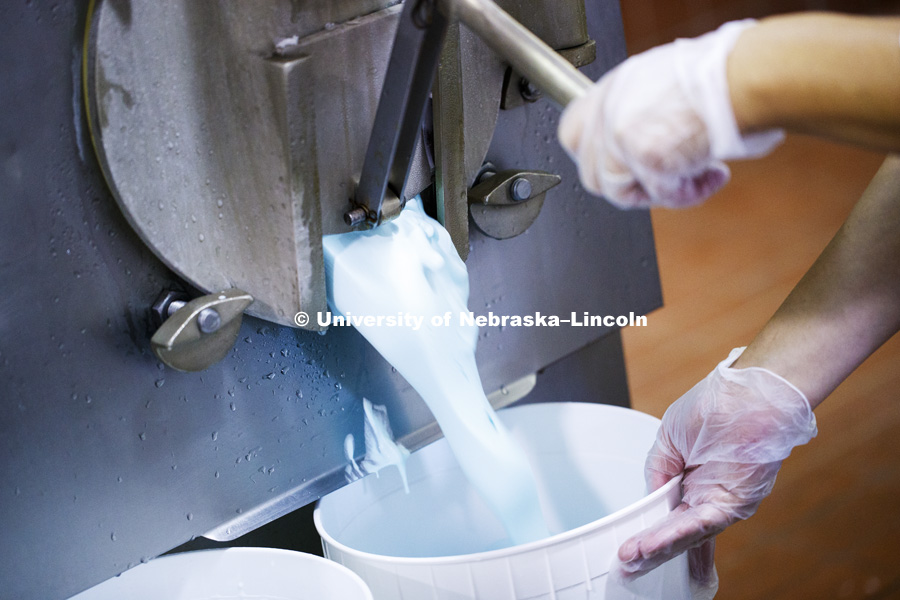 The first batch pours into the bucket. From there, the lid is added and it moves to the freezer. Dairy Store making Shark Week ice cream with gummy sharks in a light blue ice cream. July 18, 2018. Photo by Craig Chandler / University Communication.