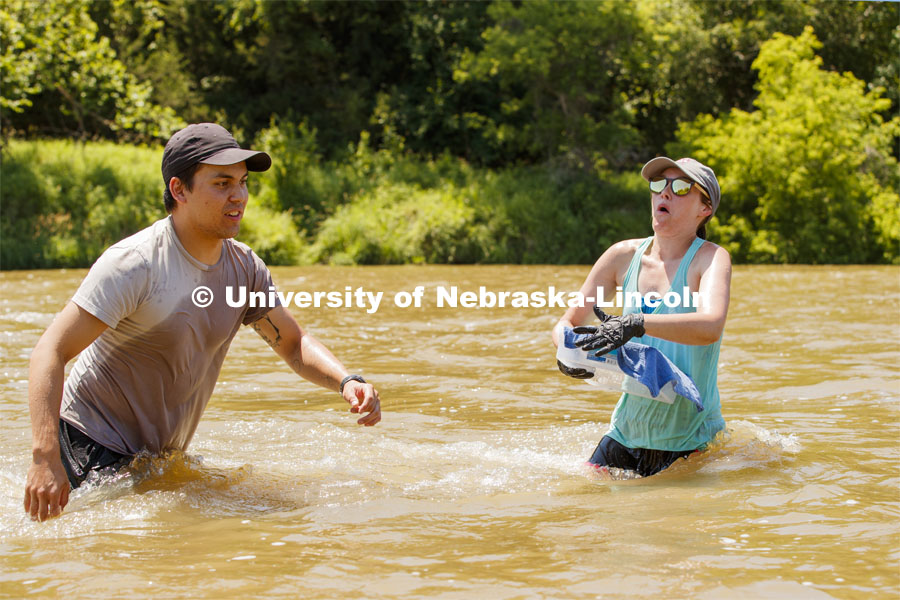 Kayla Vondracek slips and nearly loses her balance as she and Matthew Chen collect cobble samples. Professor Jessica Corman prepares more filtered water. Jessica Corman, assistant professor in the School of Natural Resources, UCARE research group researching algae in the Niobrara River. Fort Niobrara National Wildlife Refuge. July 12, 2019. Photo by Craig Chandler / University Communication.