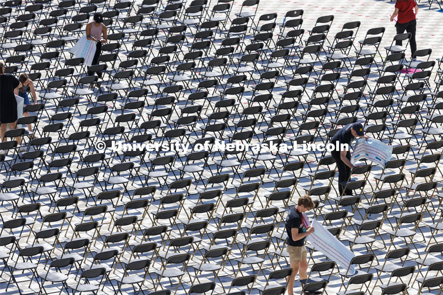 Chairs for Saturday’s undergraduate commencement in Memorial Stadium have been set up and seat numbers are being placed by volunteers. Mats cover the new turf on the field to protect it. May 13, 2022. Photo by Craig Chandler / University Communication.