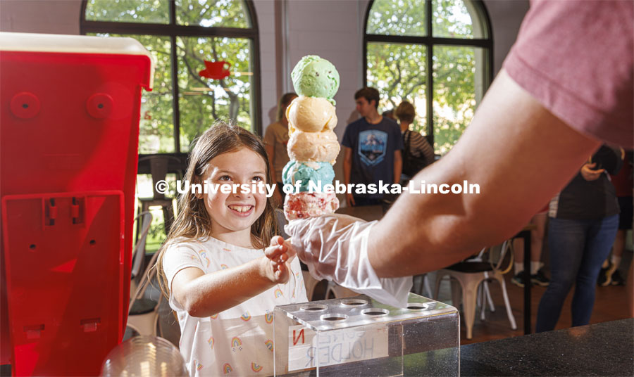 Allie Wiesman, 9, eyes a cone of colorful ice cream. She and her parents are visiting from Kentucky. Ice cream is scooped up at the Dairy Store on East Campus. July 18, 2022. Photo by Craig Chandler / University Communication.
