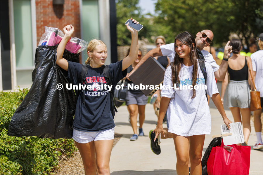 Stella Minge, left, let’s loose a yell as she and Lily Tobin, both of Omaha, head for their Schramm Hall room. Lily’s dad, B.J, photobombed the scene. Residence Hall move in for students participating in Greek Rush. August 14, 2022. Photo by Craig Chandler / University Communication.