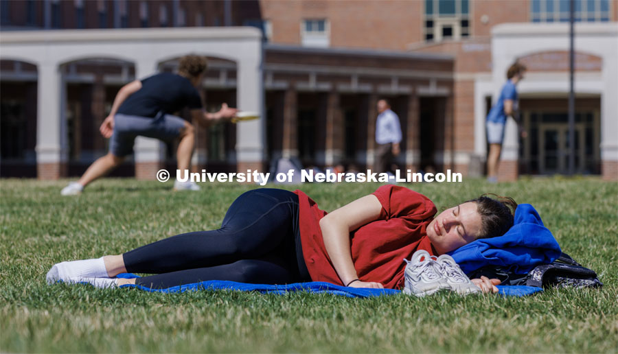 Elizabeth Denevan, a freshman from Sioux Falls, South Dakota, naps in the sunshine. When awoken, she did not her parents said how cold and rainy it was back home today. Spring on city campus. April 10, 2023. Photo by Craig Chandler / University Communication.