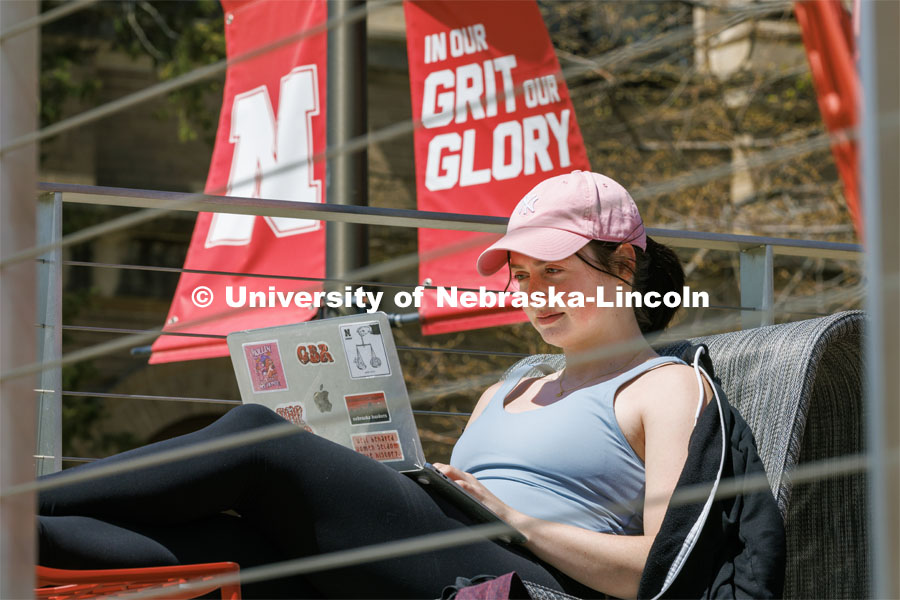 Sarah Frett, junior from Grimes, Iowa, studies on the porch outside the Nebraska East Union. Spring on East Campus. April 18, 2023. Photo by Craig Chandler / University Communication.