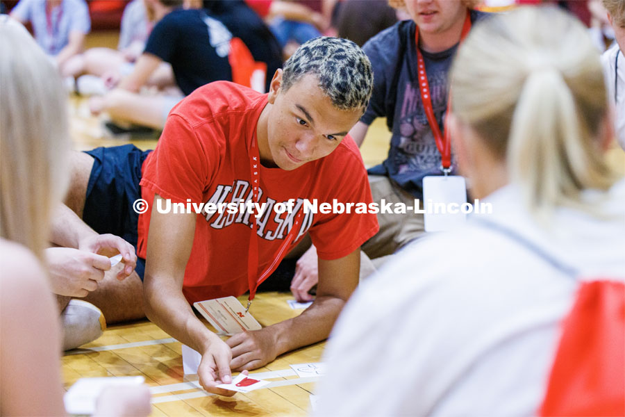 Braytn Nespor of Omaha stretches to place his card onto a pile. NSE students were sorting cards into piles organized by things to do this summer and when they arrive on campus. New Student Enrollment. June 7, 2023. Photo by Craig Chandler / University Communication.