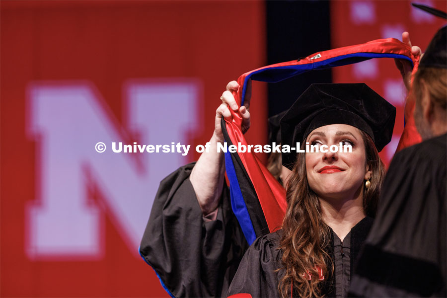 Sonia Lindner watches as her doctoral hood is placed over her head. The University of Nebraska–Lincoln is conferring 588 degrees during the combined graduate and undergraduate commencement ceremony at Pinnacle Bank Arena. August 12, 2023. Photo by Craig Chandler/ University Communication.