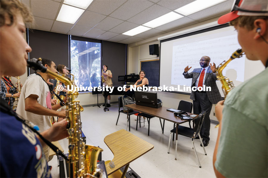 Chancellor Rodney Bennett follows the direction of Drum Major Steffani Nolda, center, and saxophone section leader Cyphers Stewart as Bennett helps lead the saxophone section in the fight song. Cornhusker Marching Band practice. August 17, 2023. Photo by Craig Chandler/ University Communication.