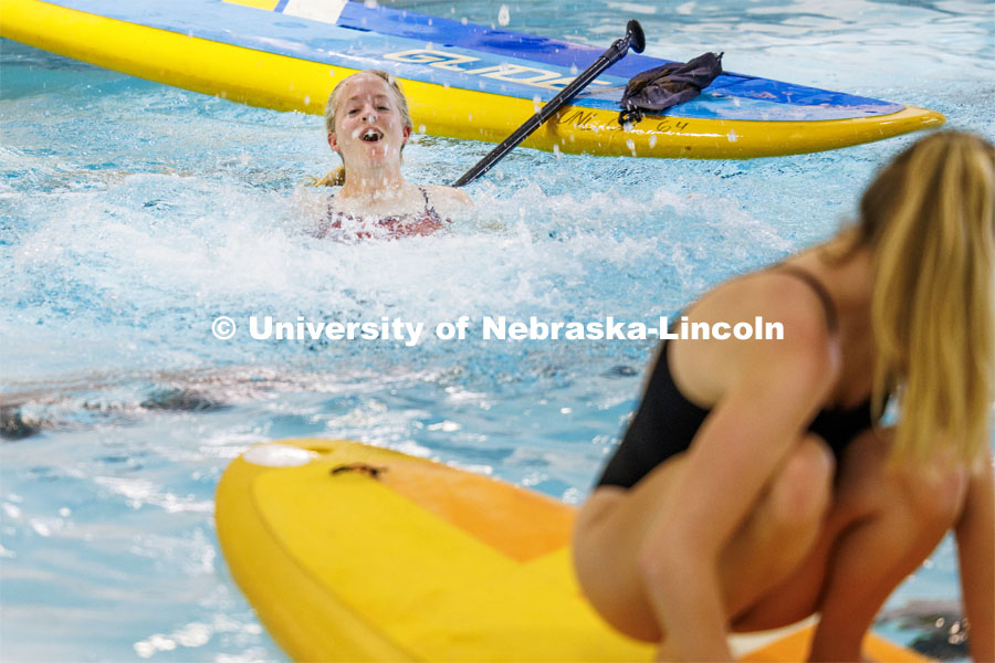 Grace Sandbulte makes a splash after attempting a handstand on a paddleboard. Paddleboard Yoga in the rec center pool as part of National Women's Health and Fitness Day. September 27, 2023. Photo by Craig Chandler / University Communication.