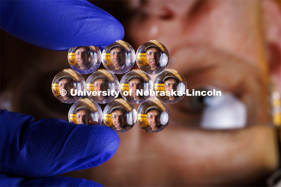 The visage of Stephen Morin, Associate Professor of Chemistry, refracts through an array of lenses to illustrate his work with manufacturing incredibly small lenses. Morin has developed a method for microprinting lenses as small at 5 microns. Approximately 2,500 of the lenses could fit on the head of a pin. October 16, 2023. Photo by Craig Chandler / University Communication.