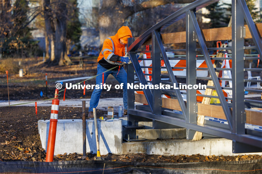 Lukas Lorenz with Judds Brothers Construction aligns the bridge as it is lowered onto the bolts on the west side of the creek. A new footbridge over Dead Mans Run on East Campus’ Maxwell Arboretum. December 5, 2023. Photo by Craig Chandler / University Communication and Marketing.