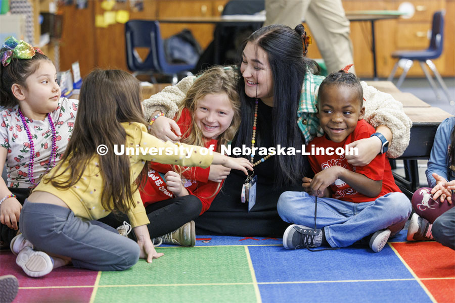 Crandall Blake student hugs BrynLee Van Dyke, left, and Lavarius Hart during group time in her kindergarten class. Blake was back in class for one last day after student teaching at Lakeview Elementary. She had her students sign a pair of white high-top shoes which she will wear at commencement so “her entire class can walk across stage with her”. December 13, 2023. Photo by Craig Chandler / University Communication and Marketing.