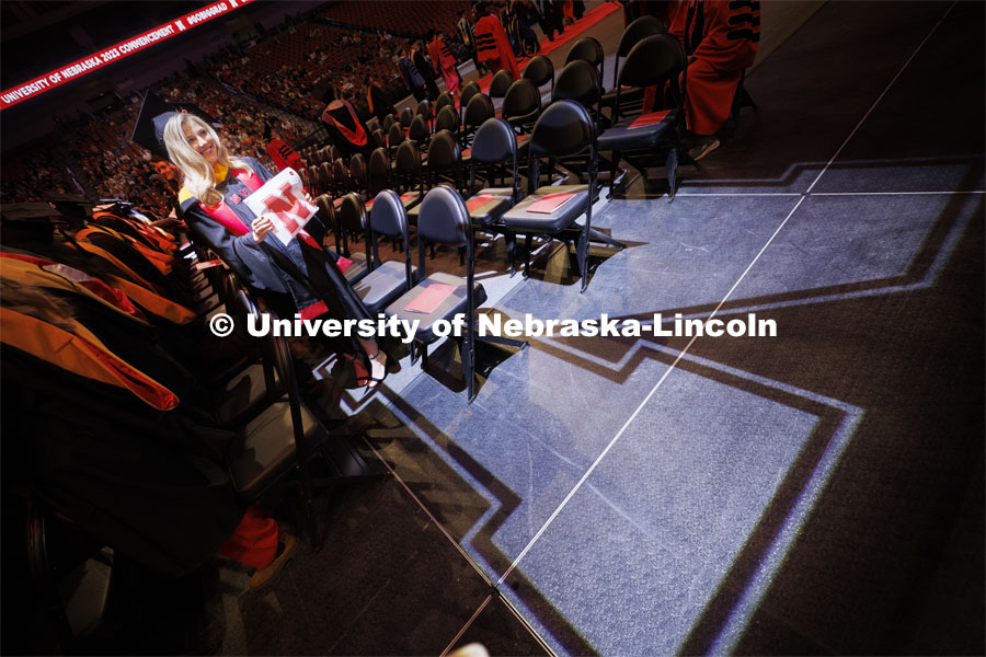 Lauren Williams shows her master’s degree in nutrition and health sciences as the “N” spotlight highlights her during the recessional. Graduate Commencement at Pinnacle Bank Arena. December 15, 2023. Photo by Craig Chandler / University Communication and Marketing.