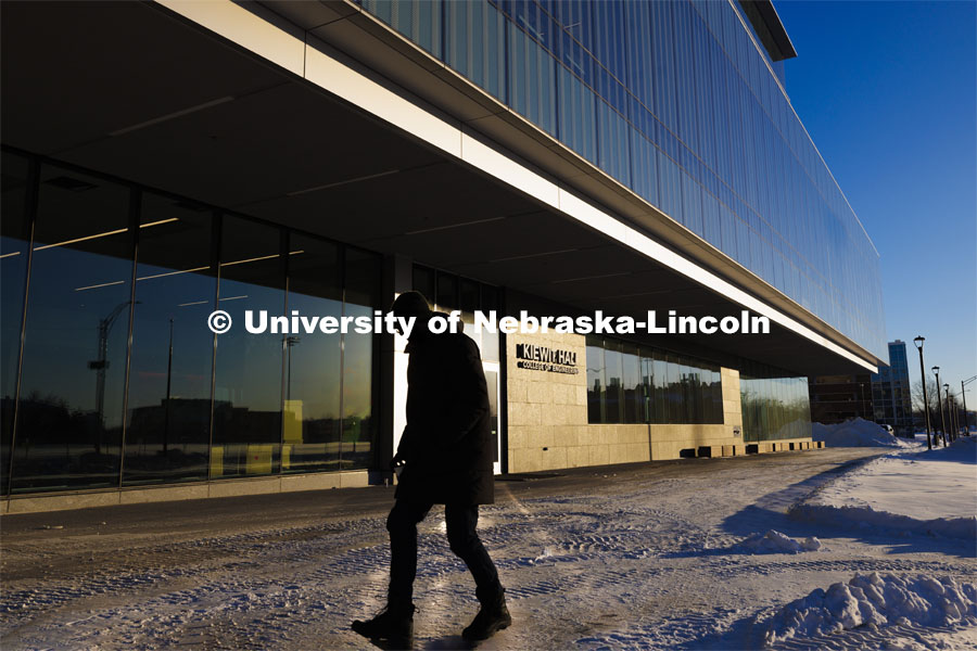 A cold Husker walks past the Kiewit Hall entrance. January 16, 2024. Photo by Craig Chandler / University Communication and Marketing.
