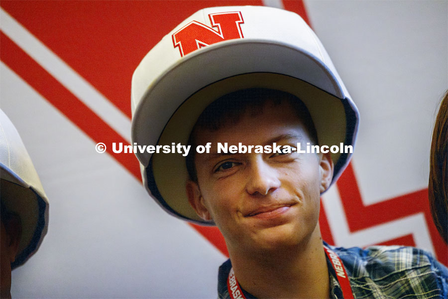 Caleb Kelly poses wearing oversized Nebraska baseball caps. Admitted Student Day is UNL’s in-person, on-campus event for all admitted students. March 23, 2024. Photo by Craig Chandler / 