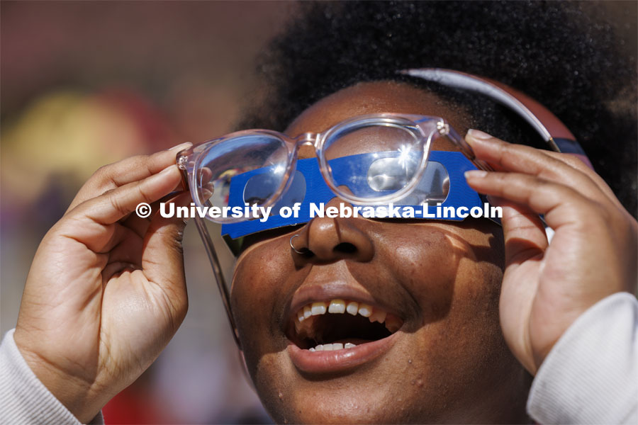 Samya Lee, a freshman from Omaha, smiles as she can see the eclipse by holding her eyeglasses over the eclipse glasses. The Solar Social party to view the partial solar eclipse filled the greenspace outside the Nebraska Union on City Campus. April 8, 2024. Photo by Craig Chandler / University Communication and Marketing.