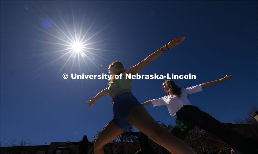 Mekenzie Horihan and Maggie Martin do yoga on the greenspace during the eclipse. The Solar Social party to view the partial solar eclipse filled the greenspace outside the Nebraska Union on City Campus. April 8, 2024. Photo by Craig Chandler / University Communication and Marketing.