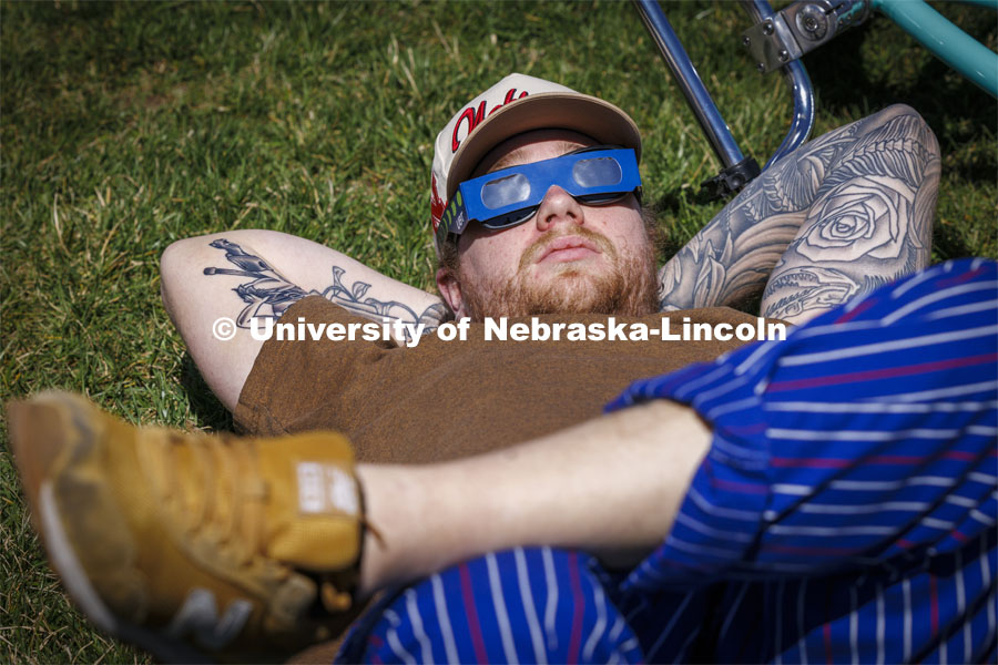 Nico Janda stretched out in the grass to watch the eclipse. The Solar Social party to view the partial solar eclipse filled the greenspace outside the Nebraska Union on City Campus. April 8, 2024. Photo by Craig Chandler / University Communication and Marketing.
