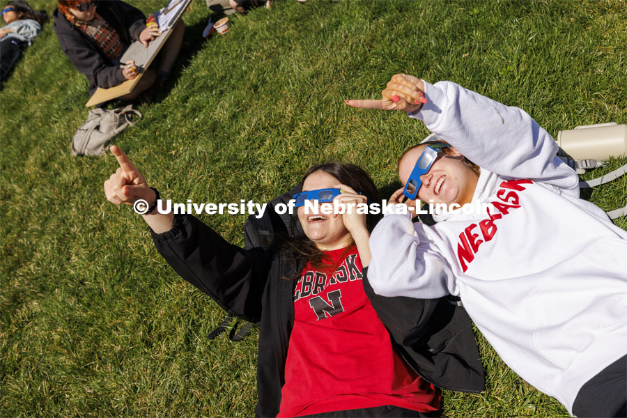 Julia Connealy and Jesse Trout watch the eclipse from the greenspace on City Campus. The Solar Social party to view the partial solar eclipse filled the greenspace outside the Nebraska Union on City Campus. April 8, 2024. Photo by Craig Chandler / University Communication and Marketing.