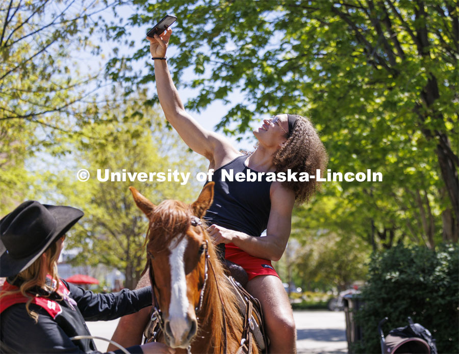 Josiah Allick takes a selfie as he rides Popsicle being led by Rodeo Club member Jaya Nelson. The Nebraska Rodeo Team gave Huskers a chance to be up close to their horses and even go for a ride. The team filled the space northwest of the Union to help promote their Nebraska Cornhusker College Rodeo being held Friday and Saturday. April 29, 2024. Photo by Craig Chandler / University Communication and Marketing.