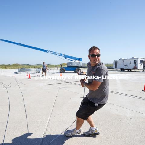 Alex Russell, a testing and maintenance technician, who has worked at the facility for 22 years since completing his undergrad degree, stretches the cable to get out the slack before it is attached to the test truck. The boom in the background will be
