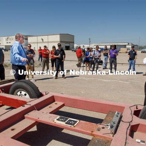 Ron Faller, left, and Bob Bielenberg, right, explain various test areas of the facility to the NASCAR tour group. Test of bull-nose barrier for use in medians to protect cars from overpass columns. Test was at university's Midwest Roadside Safety Facilty at the Lincoln airport. June 5, 2018. Photo by Craig Chandler / University Communication