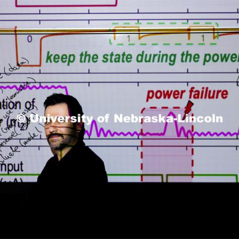 Arman Roohi, Assistant Professor in the School of Computing, is a CAREER awardee. His project is focused on developing algorithms/software to enable battery-less edge intelligence. The self-powered Internet of Things: smarter devices, greener planet. The graph behind him shows IoT nodes can operate autonomously and sustainably to realize instant computing and efficient learning, although power failures can occur because of ambient energy sources. March 12, 2024. Photo by Craig Chandler / University Communication and Marketing.