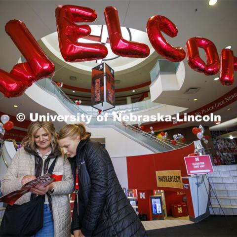 Misty and Kaegan Fredrickson of Britton, South Dakota, look over the program under a welcoming balloon arch in the Nebraska Union. Admitted Student Day is UNL’s in-person, on-campus event for all admitted students. March 23, 2024. Photo by Craig Chandler / University Communication and Marketing.