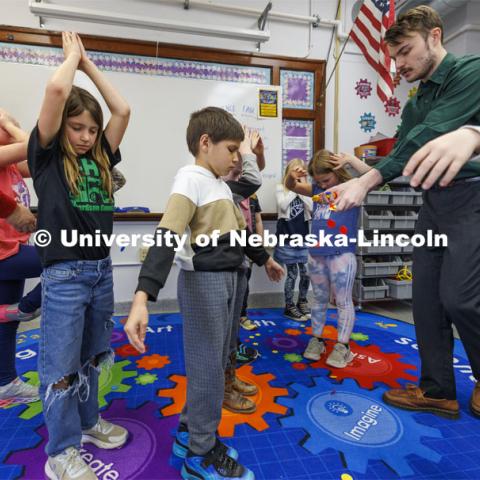 While students close their eyes and pretend they are trees, Jack Hilgert, drops red, yellow and blue chips on the floor. The chips represent nutrients, sunshine and water. The students then open their eyes and scramble to pick up a balance of chips to help their “trees” grow. Jack Hilgert, Conservation Education Coordinator for the Nebraska Forest Service, teaches second graders about trees at Humboldt-Table Rock-Steinauer school in Humboldt, Nebraska. Each student was given a Colorado blue spruce seedling to raise in the classroom while they learn about trees. March 25, 2024. Photo by Craig Chandler / University Communication and Marketing.