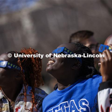 Nyarial Nyoak watches the eclipse with her friends. The Solar Social party to view the partial solar eclipse filled the greenspace outside the Nebraska Union on City Campus. April 8, 2024. Photo by Craig Chandler / University Communication and Marketing.