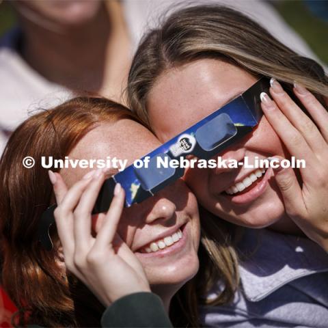Maddie Dorn and Emily Pals share their glasses to watch the eclipse. The Solar Social party to view the partial solar eclipse filled the greenspace outside the Nebraska Union on City Campus. April 8, 2024. Photo by Craig Chandler / University Communication and Marketing.