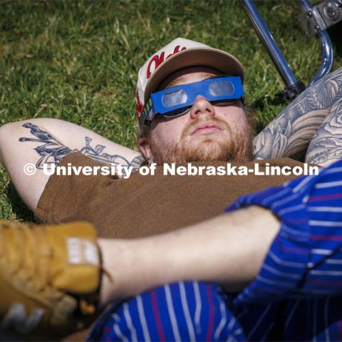 Nico Janda stretched out in the grass to watch the eclipse. The Solar Social party to view the partial solar eclipse filled the greenspace outside the Nebraska Union on City Campus. April 8, 2024. Photo by Craig Chandler / University Communication and Marketing.