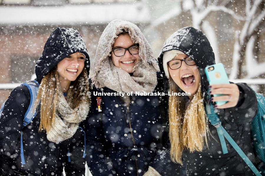 Kayla Felix, left, and Alli Hauger smile as Emily Hames takes a selfie of them while they walked to class during the hardest snow. A snow storm of large wet flakes falls on UNL Monday, January 25 2016. Photo by Craig Chandler / University Communications