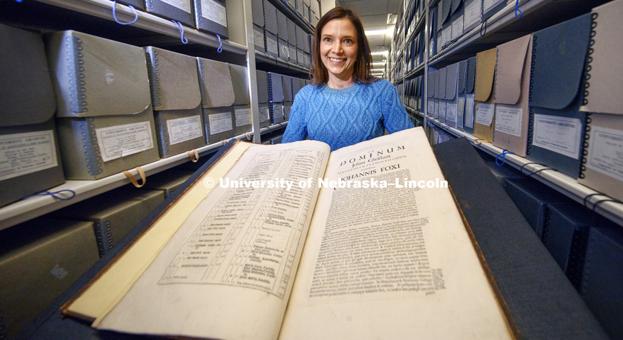 Traci Robison, the Photo and Exhibits Specialist with the the Archives and Special Collections of the University of Nebraska–Lincoln Libraries displays a 1684 book by Johannis Fox that is part of the collection's books. Photo by Craig Chandler / University Communication.