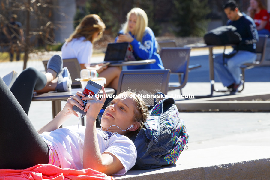 Taylor Jakub checks her phone outside the Adele Hall Learning Commons. Students enjoy a very rare sunny mid-70s February day. February 22, 2017. Photo by Craig Chandler / University Communication.