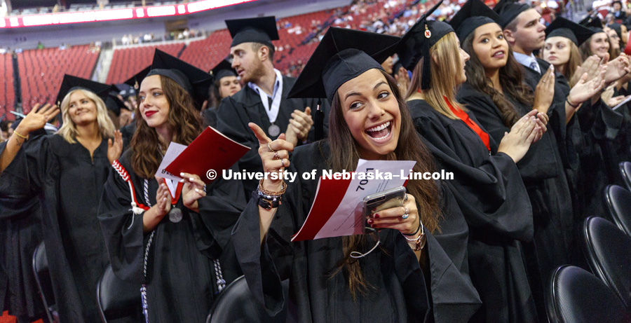 Jacqueline Abrahamson points to her family during commencement when the graduates were asked to stand and acknowledge their parents. August Commencement at Pinnacle Bank Arena. August 12, 2017. Photo by Craig Chandler / University Communication.