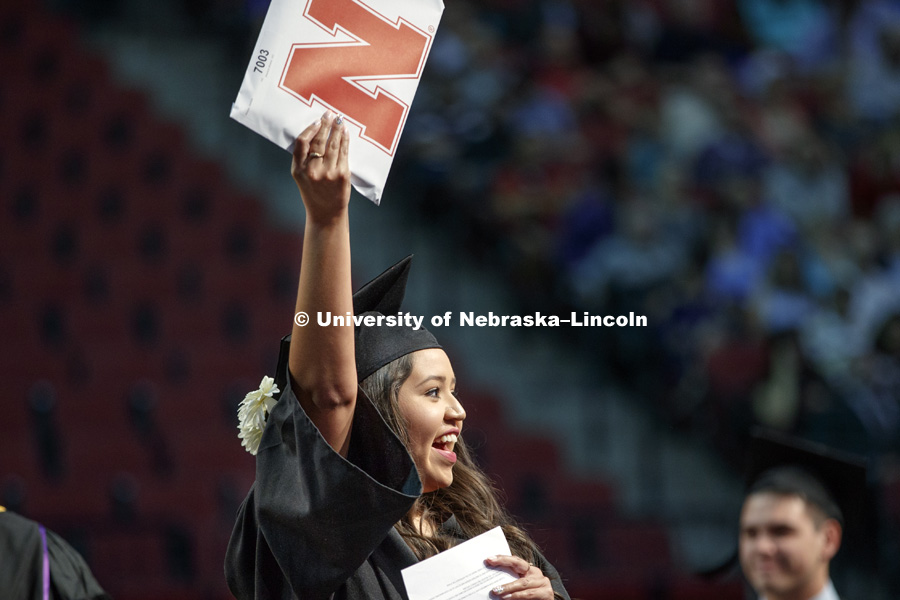 Martiza Alvarez, a first generation Husker graduate, holds up her Arts and Sciences diploma to acknowledge her family and friends. August Commencement at Pinnacle Bank Arena. August 12, 2017. Photo by Craig Chandler / University Communication.