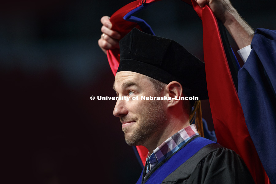 Scott Frohn watches as his doctoral hood is lowered over his head. August Commencement at Pinnacle Bank Arena. August 12, 2017. Photo by Craig Chandler / University Communication.