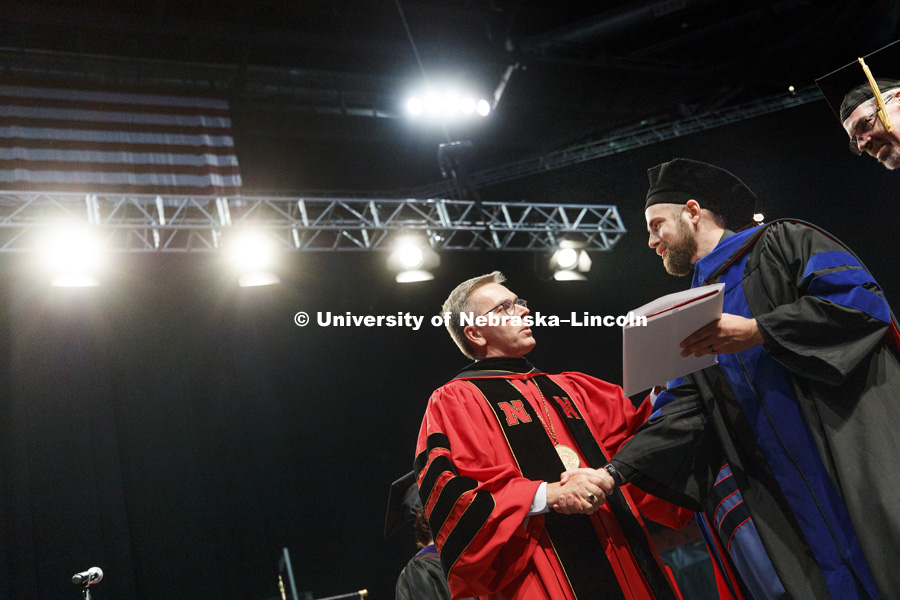Brent McKain receives congratulations from Chancellor Ronnie Green after McKain was awarded his doctoral degree. At right is McKain's faculty advisor, James Radcliffe. August Commencement at Pinnacle Bank Arena.  August 12, 2017. Photo by Craig Chandler /