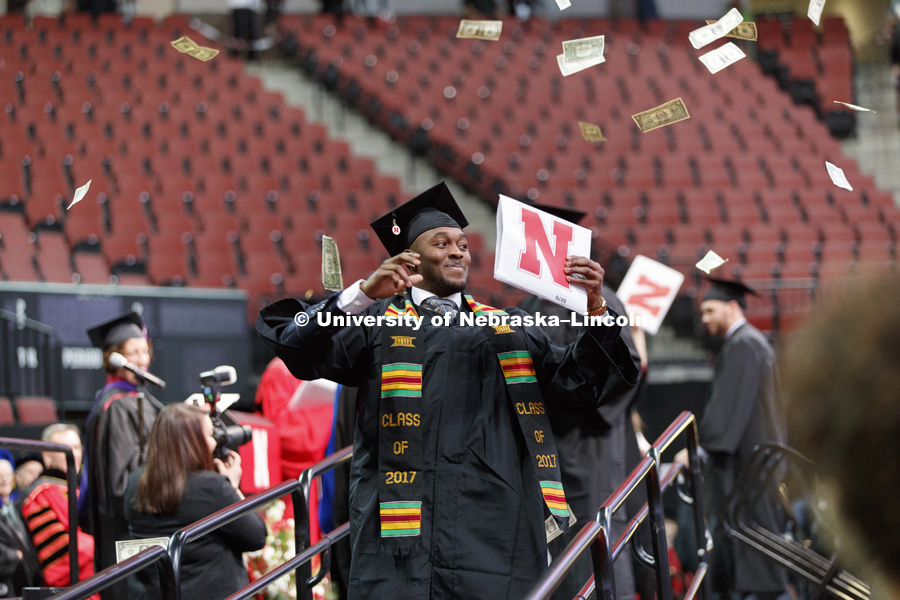 Joshua Kalu shows off his CEHS diploma after tossing a hand full of dollar bills into the air as he walked off the stage. Undergraduate Commencement at Pinnacle Bank Arena.  December 16, 2017. Photo by Craig Chandler / University Communication.