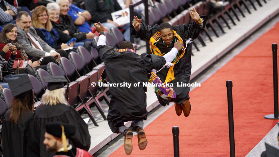 Kristoffer Bridges and an Omega Psi Phi fraternity brother celebrate on the floor after receiving their diplomas Saturday. Undergraduate Commencement at Pinnacle Bank Arena. December 16, 2017. Photo by Craig Chandler / University Communication.