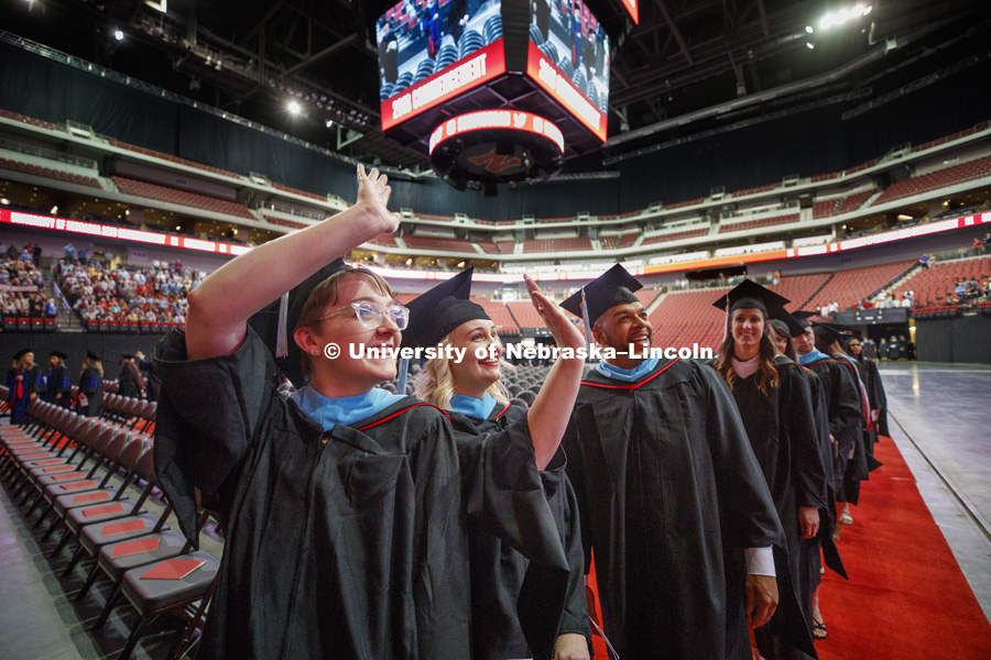 Maggie Fischer, Natalie Floreani and Phillip Foster wave to the crowd as they enter the arena with the other graduates. Graduate Commencement at Pinnacle Bank Arena. May 4, 2018. Photo by Craig Chandler / University Communication.
