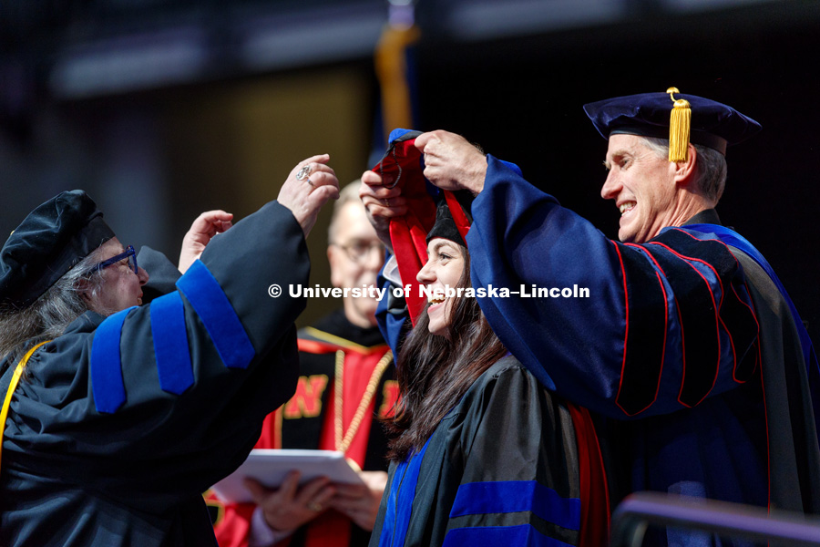 Jordan Allen is all smiles as she is hooded by Professors Dawn Braithwaite, left, and Interim Dean Timothy Carr. Graduate Commencement at Pinnacle Bank Arena. May 4, 2018. Photo by Craig Chandler / University Communication.