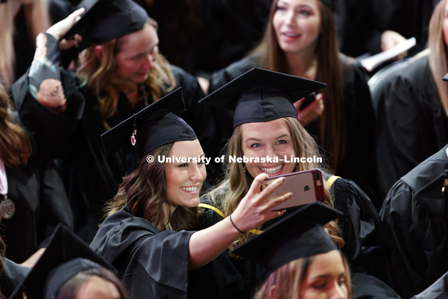 Two friends take a selfie while fellow graduates continue to file into the arena. Undergraduate Commencement at Pinnacle Bank Arena. May 5, 2018. Photo by Craig Chandler / University Communication.